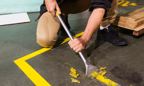OLFA XSR-600 X-Design 24" Extra Heavy-Duty Scraper in action removing worn tape from warehouse floor
